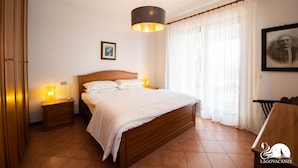 A bedroom with a wooden bed, bedside lamps, a framed picture on the wall, and a window with curtains.