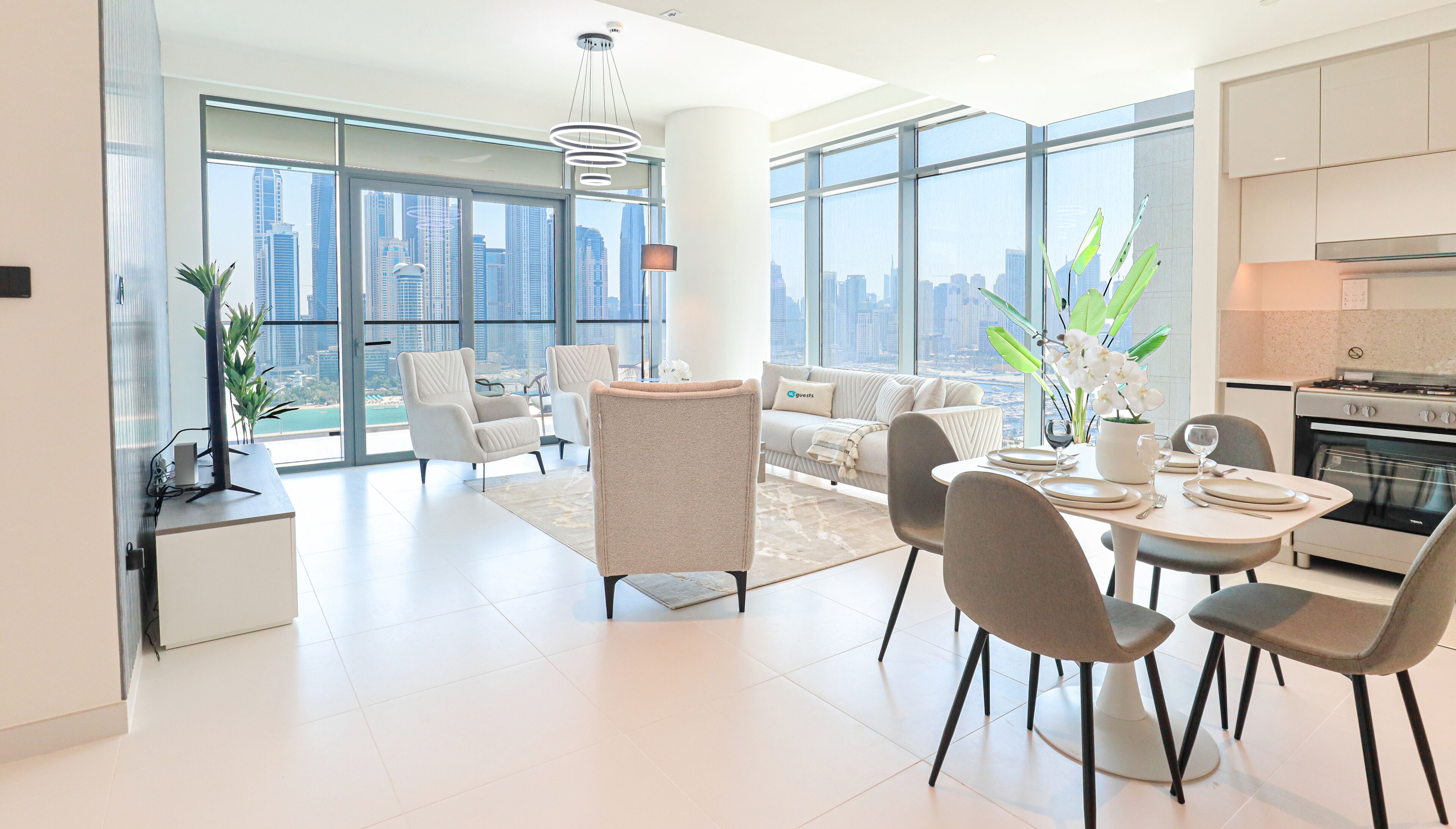 A modern living room with a sofa, chairs, a dining table set for four, and a city view through large windows.