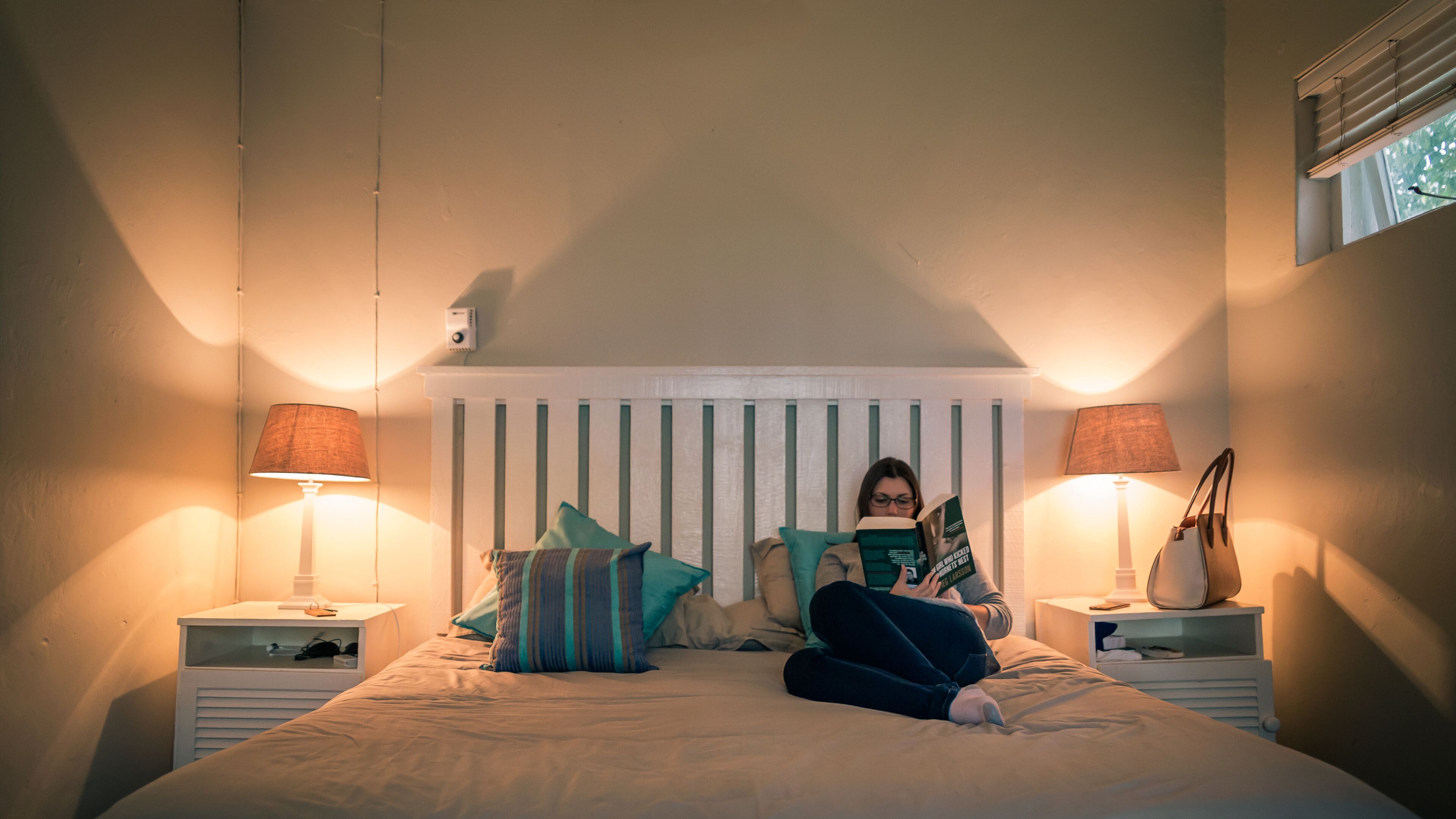 A bedroom with a bed, two bedside tables, and a window.