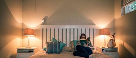 A bedroom with a bed, two bedside tables, and a window.