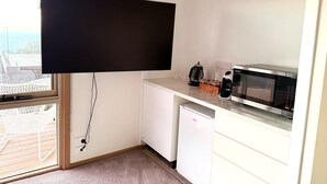 Una cuina compacta amb televisió de pantalla plana, microones, cafetera i nevera petita.