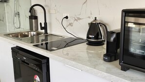 Una cuina moderna amb un vàter d'acer inoxidable, una cafetera Breville i un rentaplats.