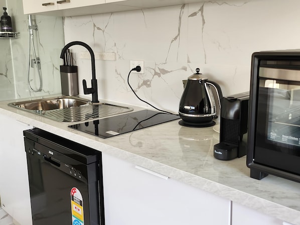 A modern kitchen with a stainless steel sink, a Breville coffee maker, and a dishwasher.
