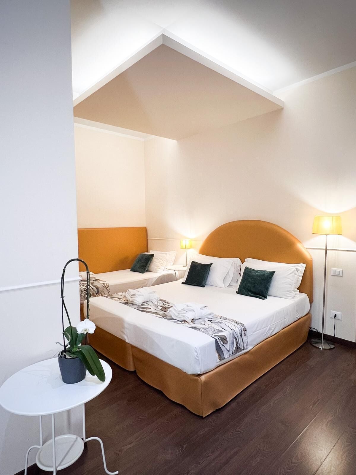 A hotel room with two beds, a small table, and a potted plant.