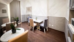 Ein Essbereich mit Tisch, Stühlen, einer Topfpflanze und einer Wand mit Einbauschränken.