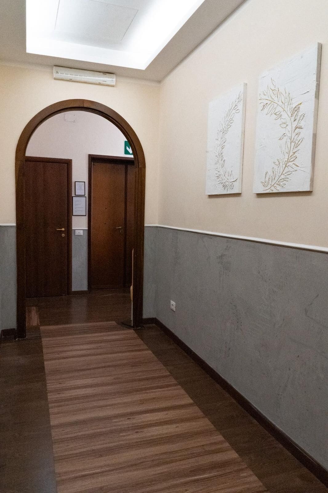 A hallway with a wooden door, a grey wall, and a patterned carpet.
