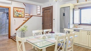 A dining area with a glass table, white chairs, and a chandelier.
