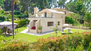 A modern villa with a spacious patio, a small pool, and lush greenery.