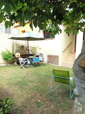 A patio with a table and chairs, a hanging chair, a potted plant, and a large umbrella.