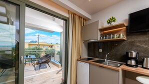 A modern kitchen with a built-in dishwasher, a coffee maker, and a TV mounted above the counter. - The Olive Land (Thasos)