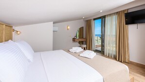 A hotel room with a large bed, a flat-screen TV, a balcony with curtains, and a view of the outdoors. - The Olive Land (Thasos)