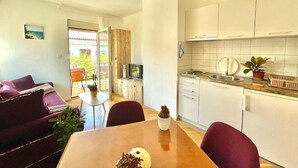 A compact living space with a dining area, kitchenette, and a view of the outdoors. - Garden House Budva (Budva)