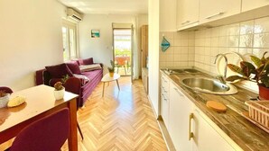 A modern kitchen with a herringbone floor, white cabinets, and a stainless steel sink. - Garden House Budva (Budva)
