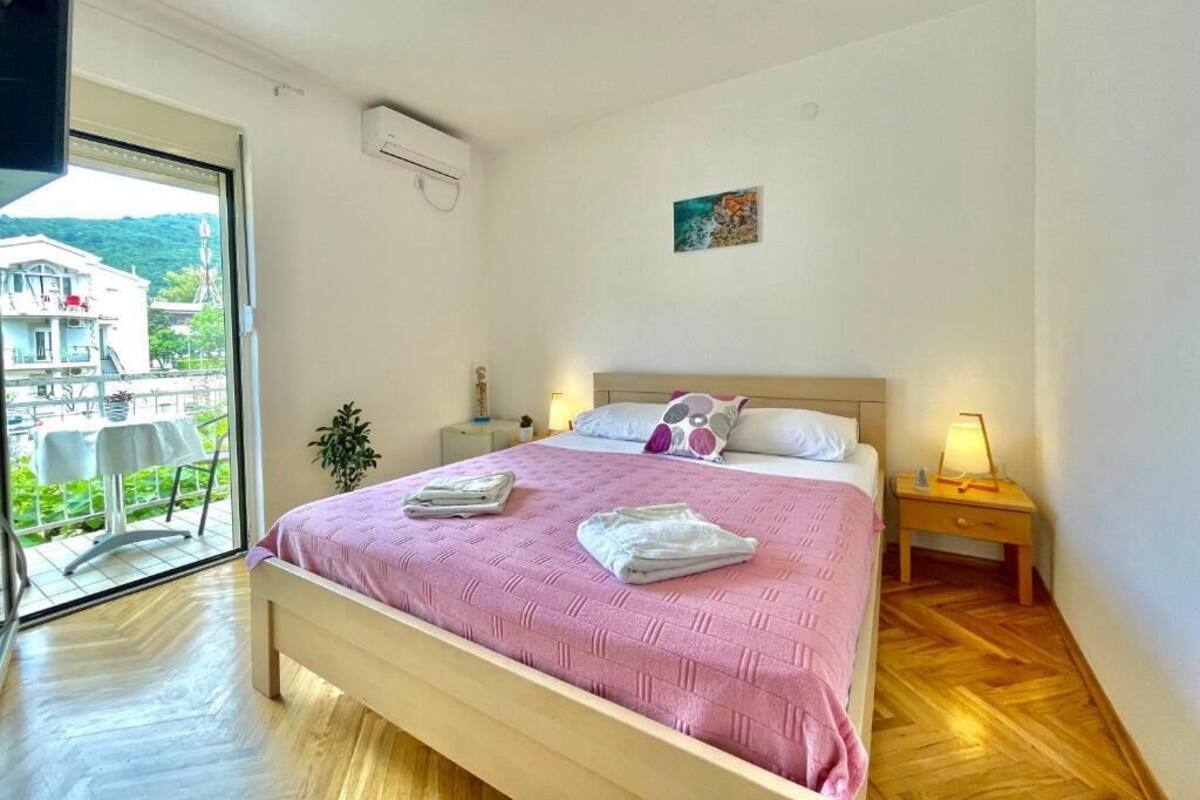 A bedroom with a bed, bedside tables, a window with a view, and a ceiling light.