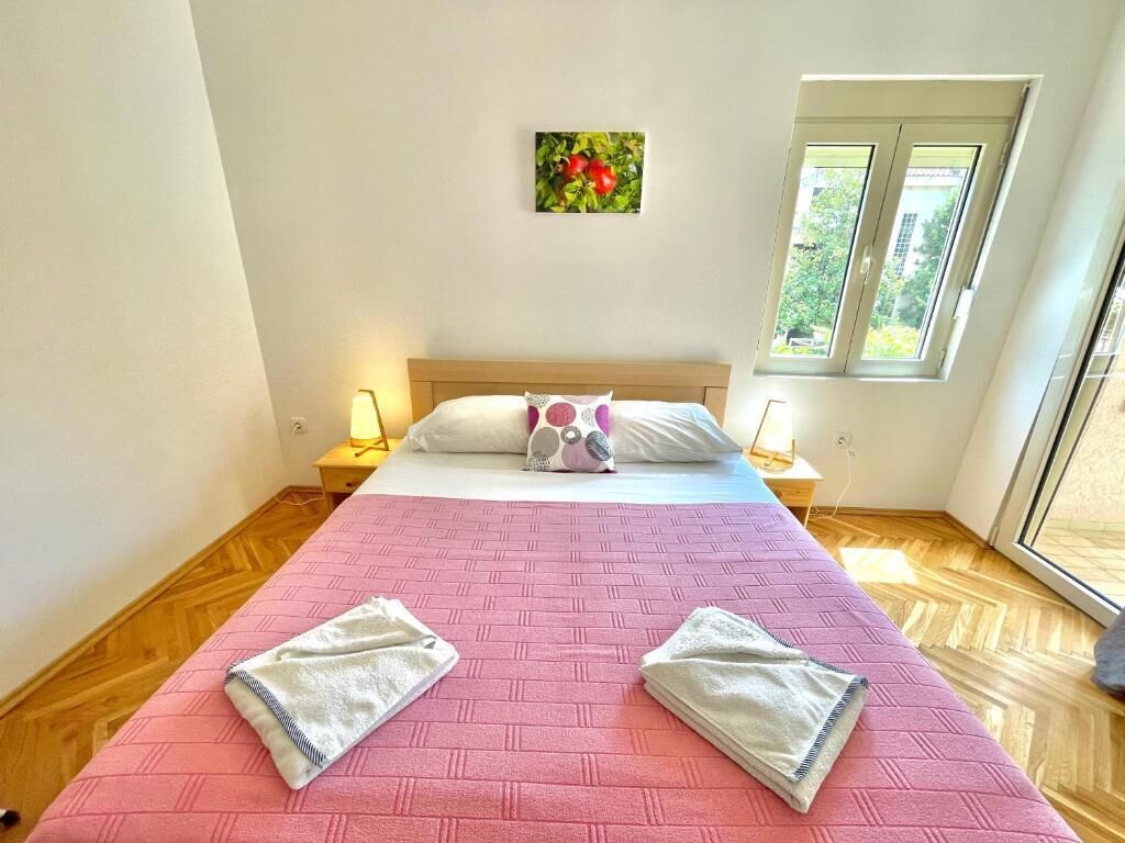 Une chambre à coucher comprenant un lit, deux tables de chevet, une fenêtre et un tableau accroché au mur.