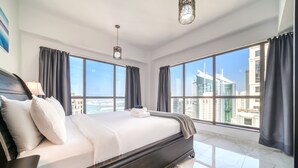 Une chambre moderne avec un grand lit, deux fenêtres et une vue sur la ville.