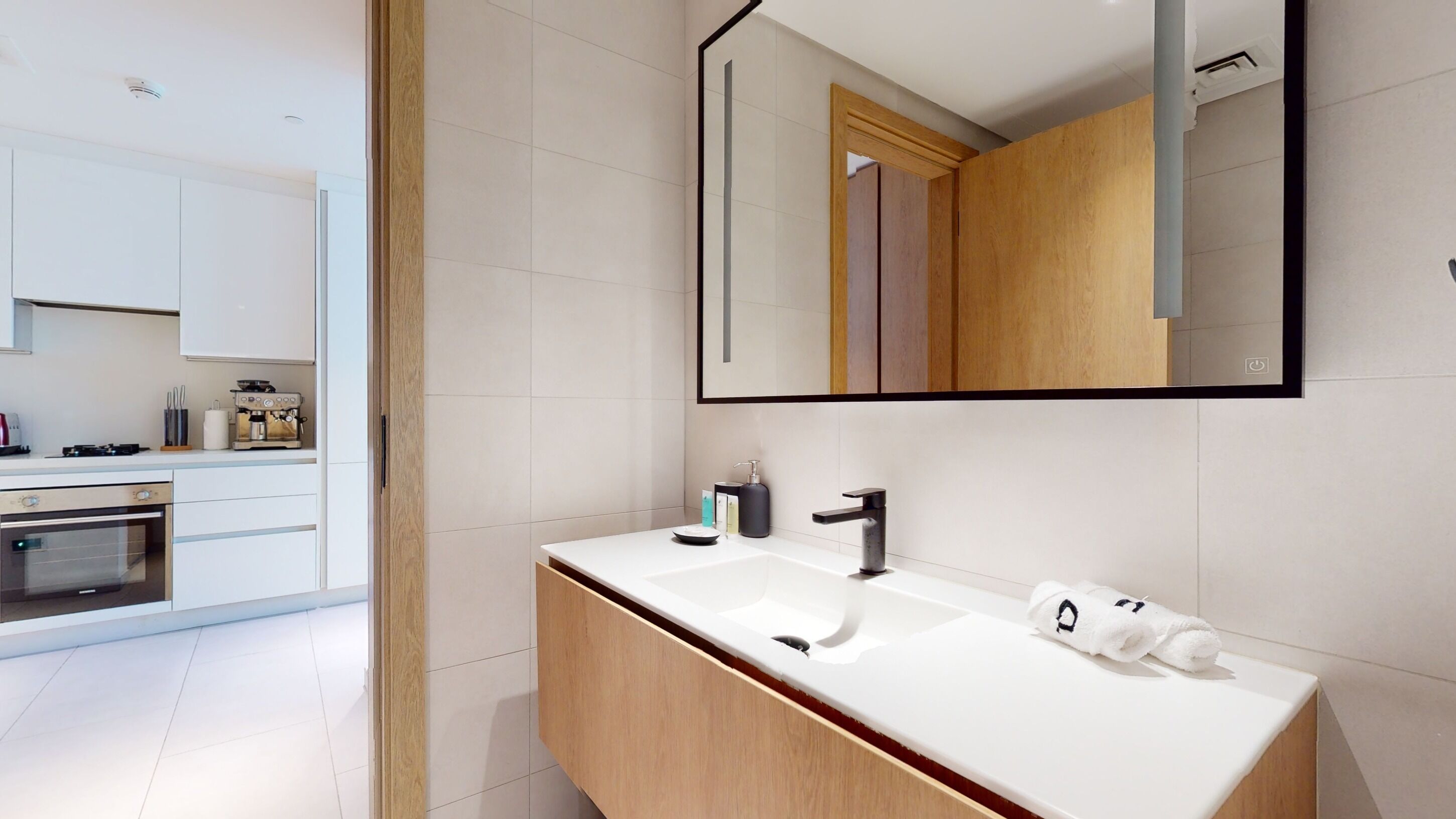 A modern bathroom with a large mirror, a sink, and a toilet.