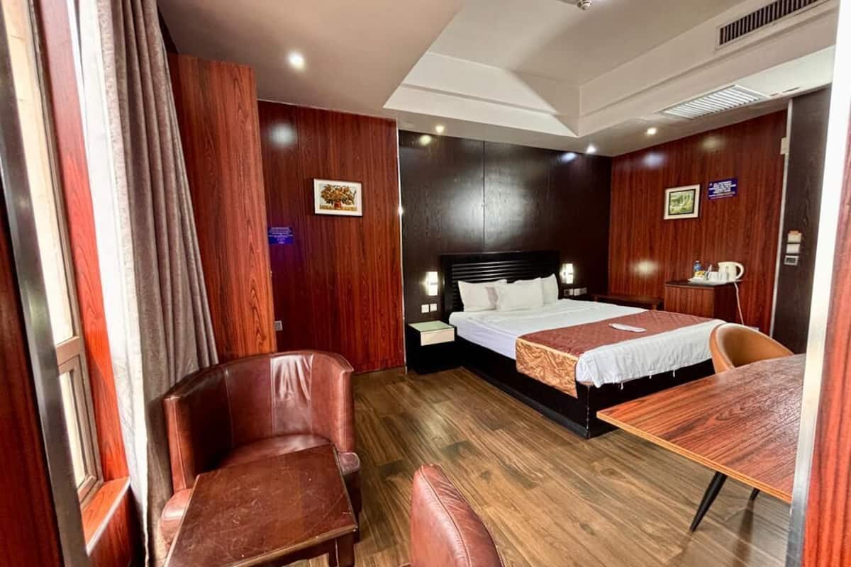 A hotel room with a bed, a desk, a chair, and a window with curtains.