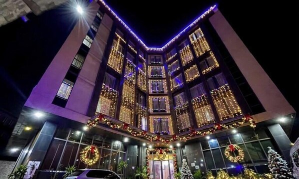 A multi-story building with a corner entrance, decorated with lights and wreaths.
