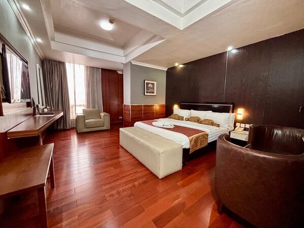 A hotel room with a large bed, a desk, a chair, and a sofa. - Airport Golden Tulip Hotel. (Lagos)