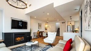 A modern living room with a fireplace, a television, and a dining area. - Tremblant Prestige - Les Eaux 215-8 (Mont-Tremblant)