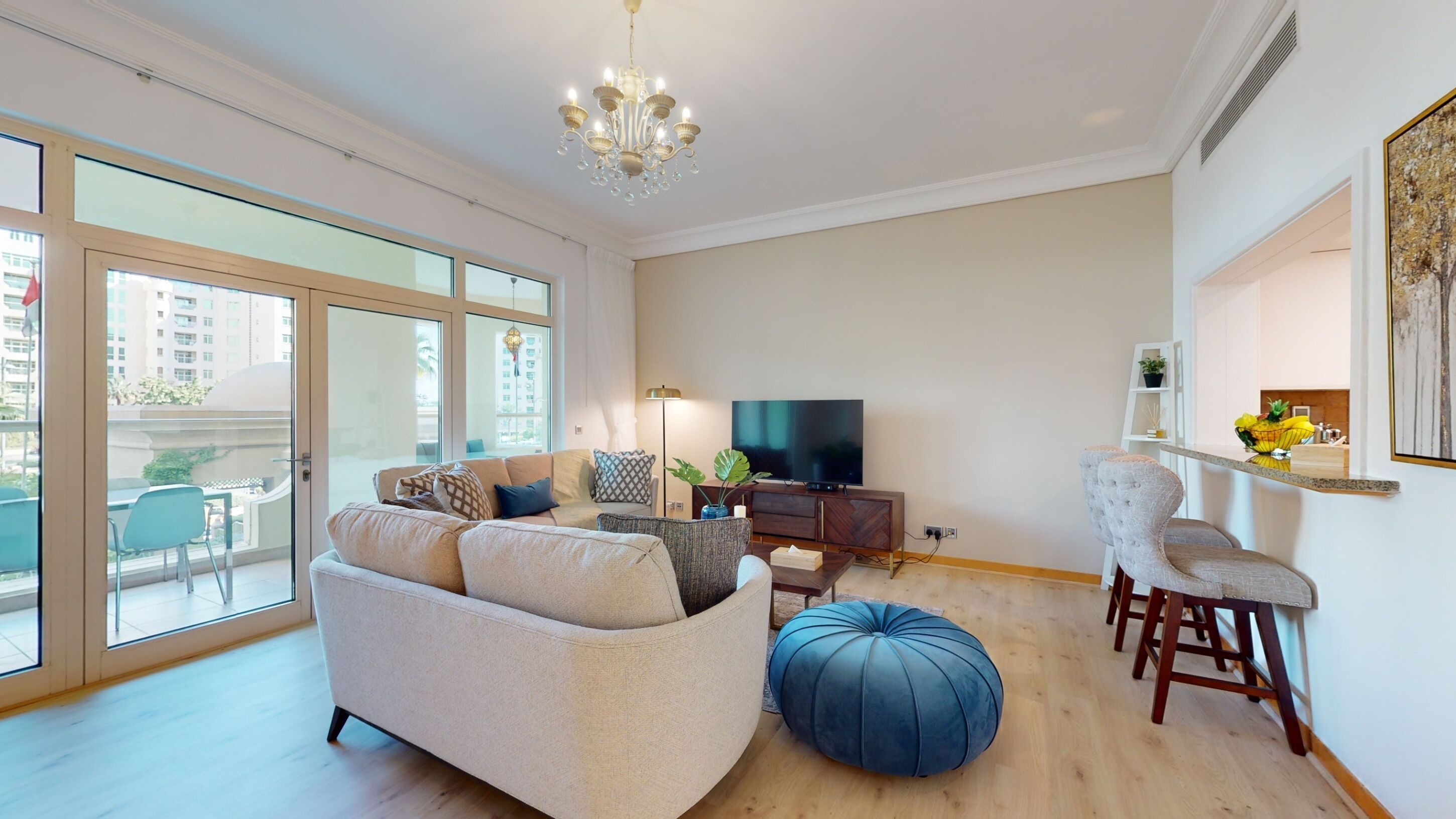 A spacious living room with a sofa, ottoman, and a TV.