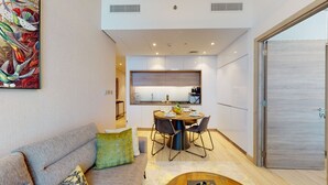 Ein modernes Wohnzimmer mit Sofa, Couchtisch und Essbereich mit Tisch für vier Personen.