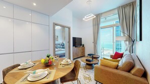 Ein modernes Hotelzimmer mit Essbereich, einer Sitzecke, einem Fernseher und einem Balkon mit Blick auf die Stadt.