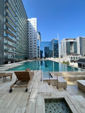 A rooftop pool area with a view of modern high-rise buildings.