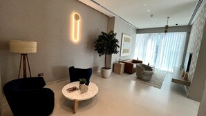 A modern living room with a round coffee table, a dark armchair, a potted plant, and a sofa. - Luxe 1BR w/ Stunning Sea Views and Infinity Pool (Dubai)