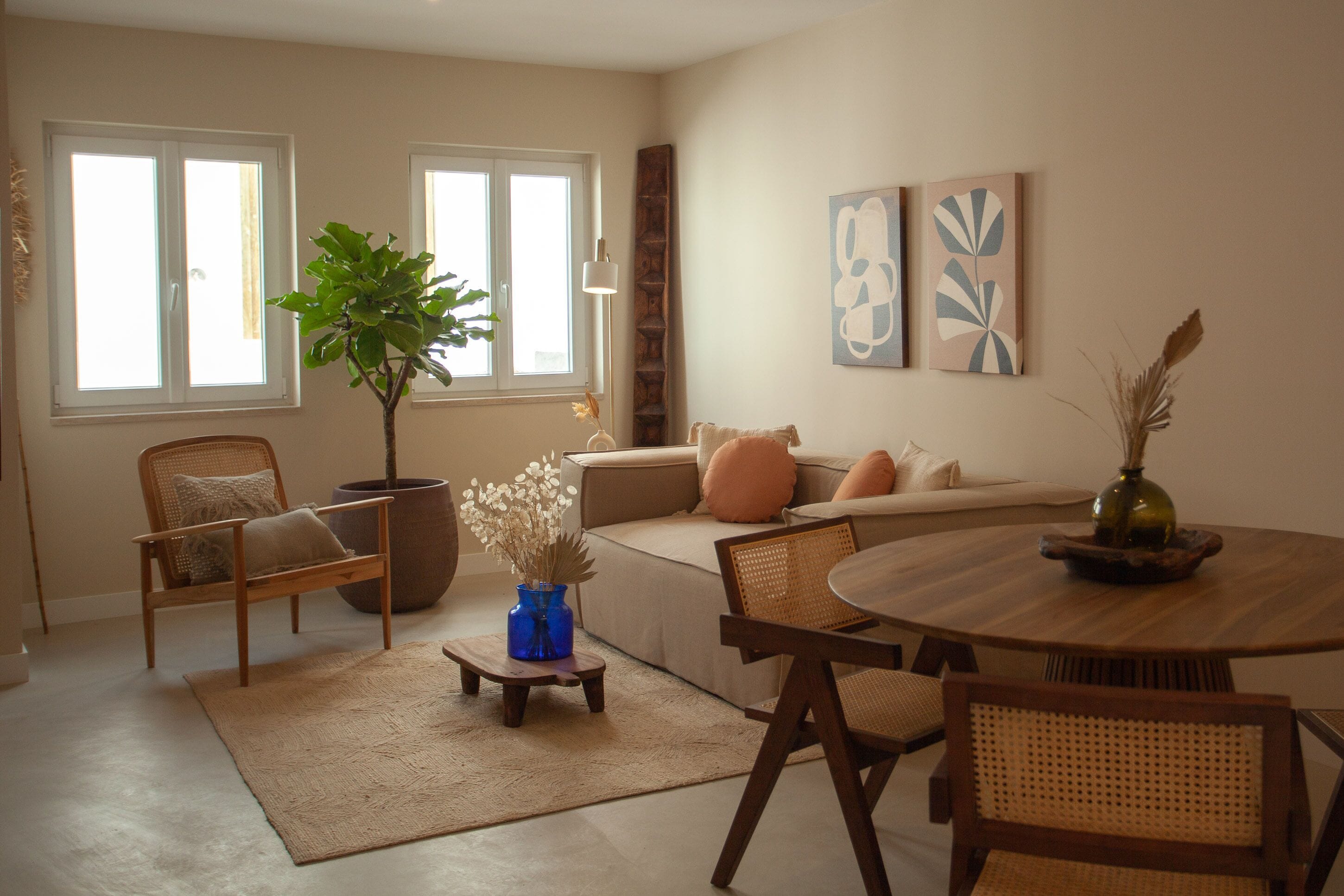 A living room with a sofa, chairs, a coffee table, and a potted plant.