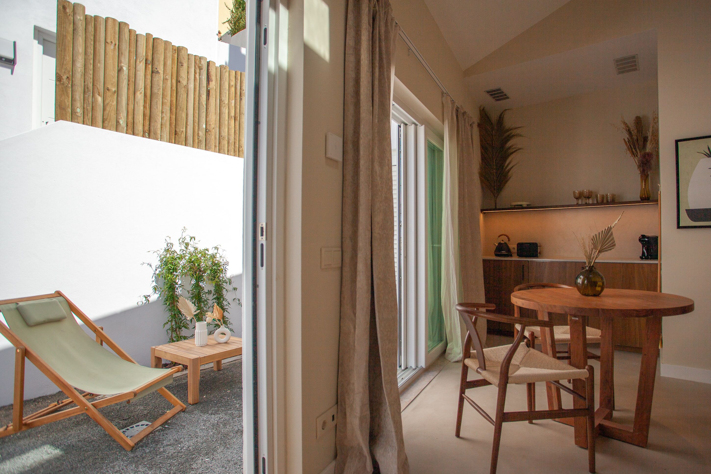 Une pièce avec une chaise en bois, une petite table et une plante en pot.