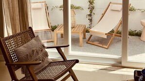 A room with a large sliding glass door leading to an outdoor area with two wooden lounge chairs and a small table. - Vila Rodrigues (Lisbon)