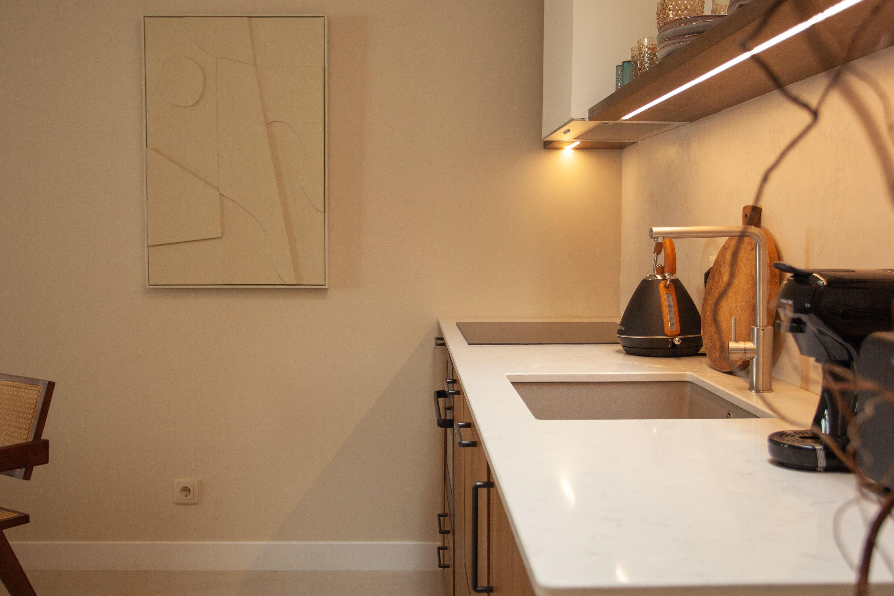Una cocina moderna con encimera blanca, cafetera y hervidor.