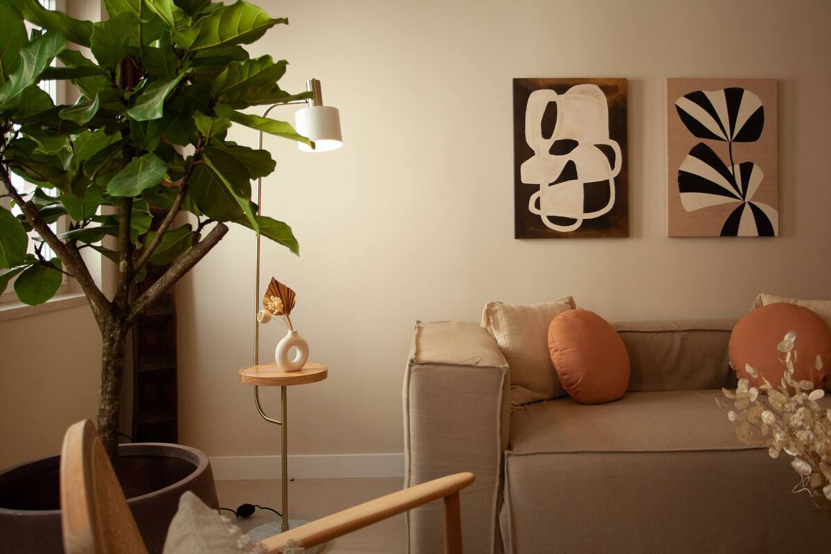A living room with a sofa, decorative pillows, a small table with a vase, and wall art.