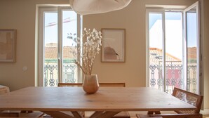 A dining area with a wooden table and chairs, a vase with dried flowers, and a framed picture on the wall. - Vila Rodrigues (Lisbon)