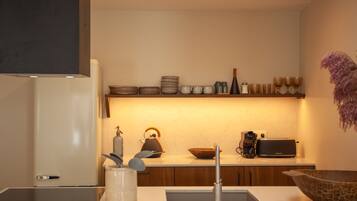 A modern kitchen with a built-in oven, a coffee maker, a toaster, and a variety of bowls and cups on the countertop.