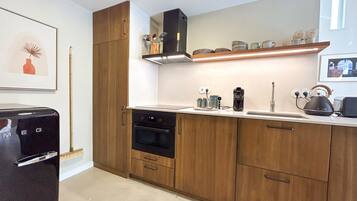 A modern kitchen with wooden cabinets, a built-in oven, a coffee machine, and a kettle on the countertop.