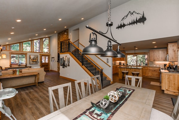 Un'ampia zona giorno con tavolo da pranzo, pavimento in legno e una scala che conduce a una mezzanine.