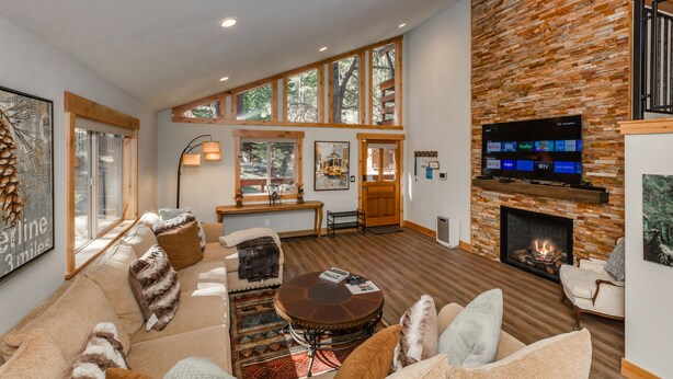A spacious living room with a fireplace, large windows, and a flat-screen TV. - Clubhouse_On Hole 10, Hot Tub, Sauna, GameRoom, Pool Table, Arcades, Walk To Hole 1 & Driving Range (Truckee)