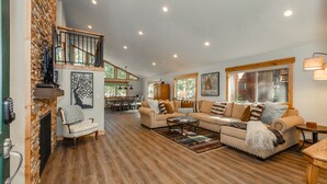 A spacious living room with a fireplace, a large sofa set, and a dining area in the background. - Clubhouse_On Hole 10, Hot Tub, Sauna, GameRoom, Pool Table, Arcades, Walk To Hole 1 & Driving Range (Truckee)