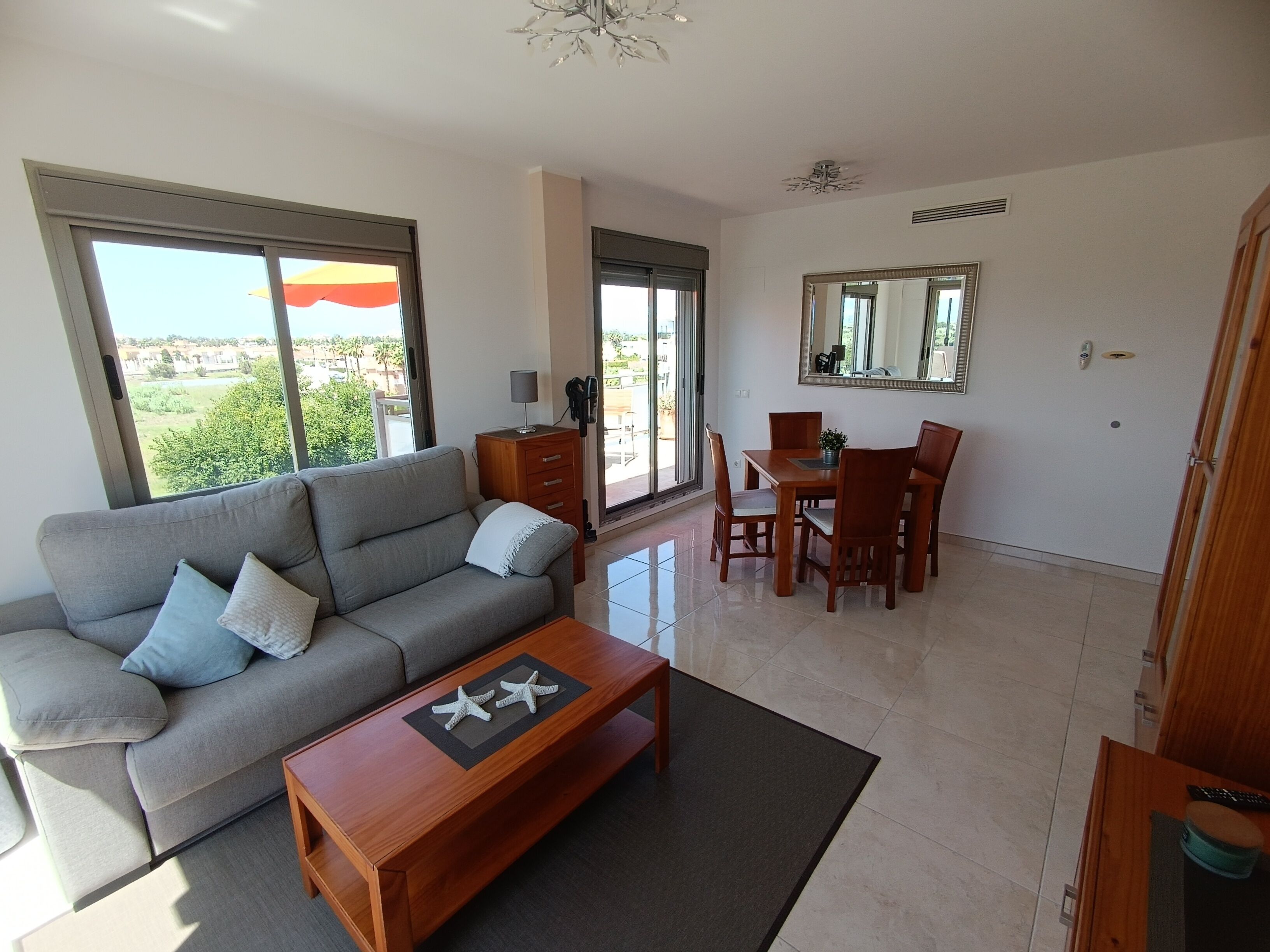 A modern living room with a sofa, coffee table, and dining area.