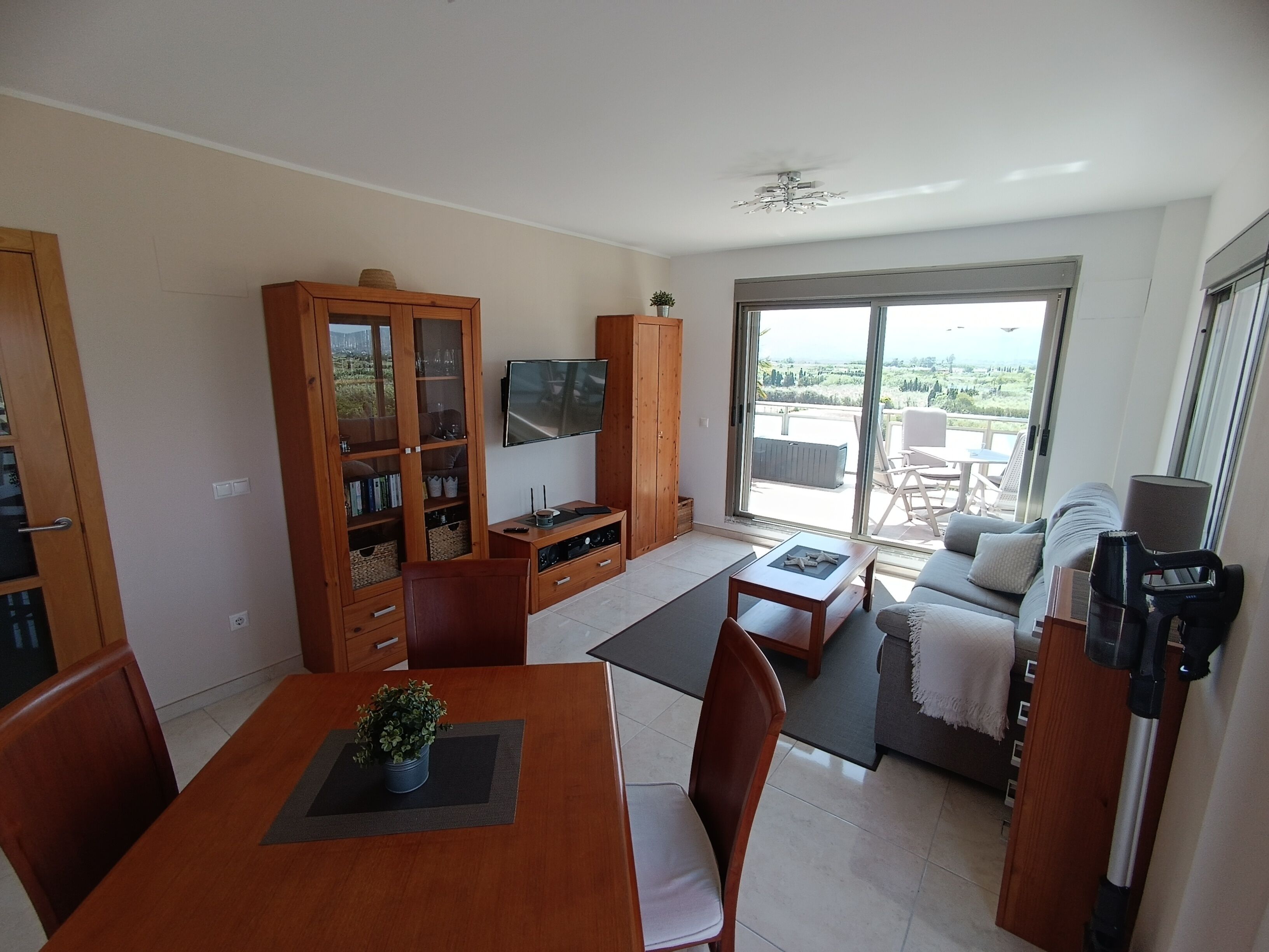 Un vaste espace de vie comprenant une table à manger, des chaises, un canapé, un téléviseur et un balcon avec vue.