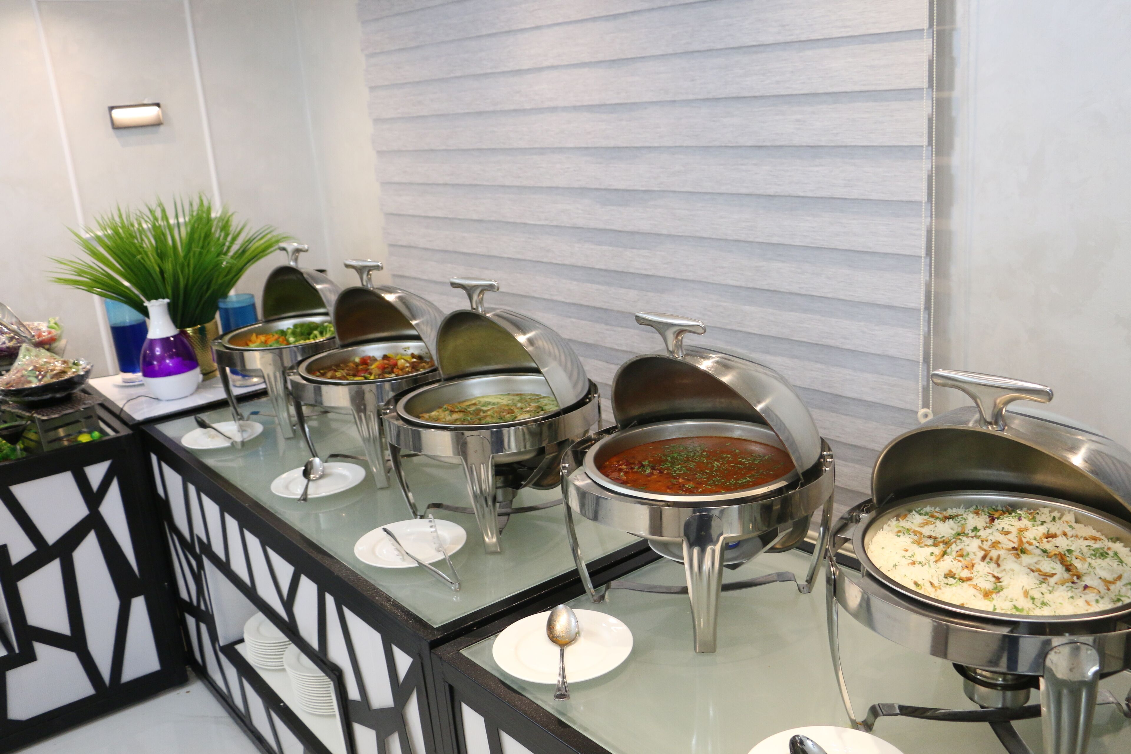 Montaje de bufé con distintas estaciones de comida, incluyendo un plato de arroz, sopa y ensalada.