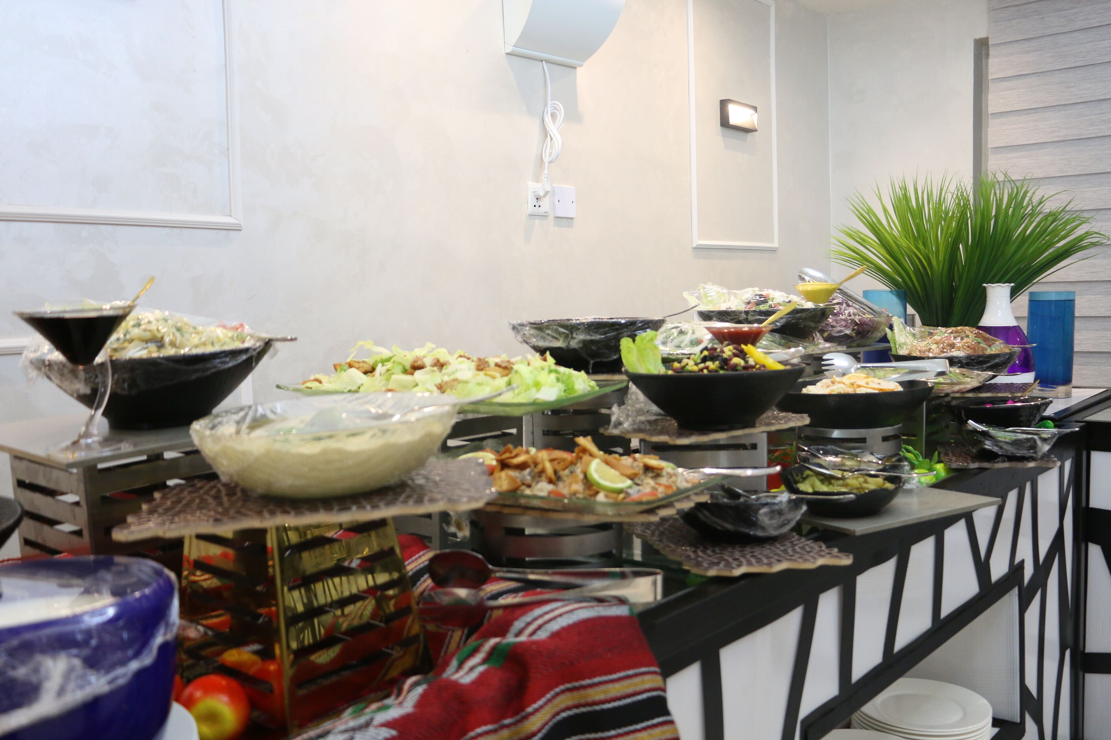A buffet setup with various dishes and a decorative plant.