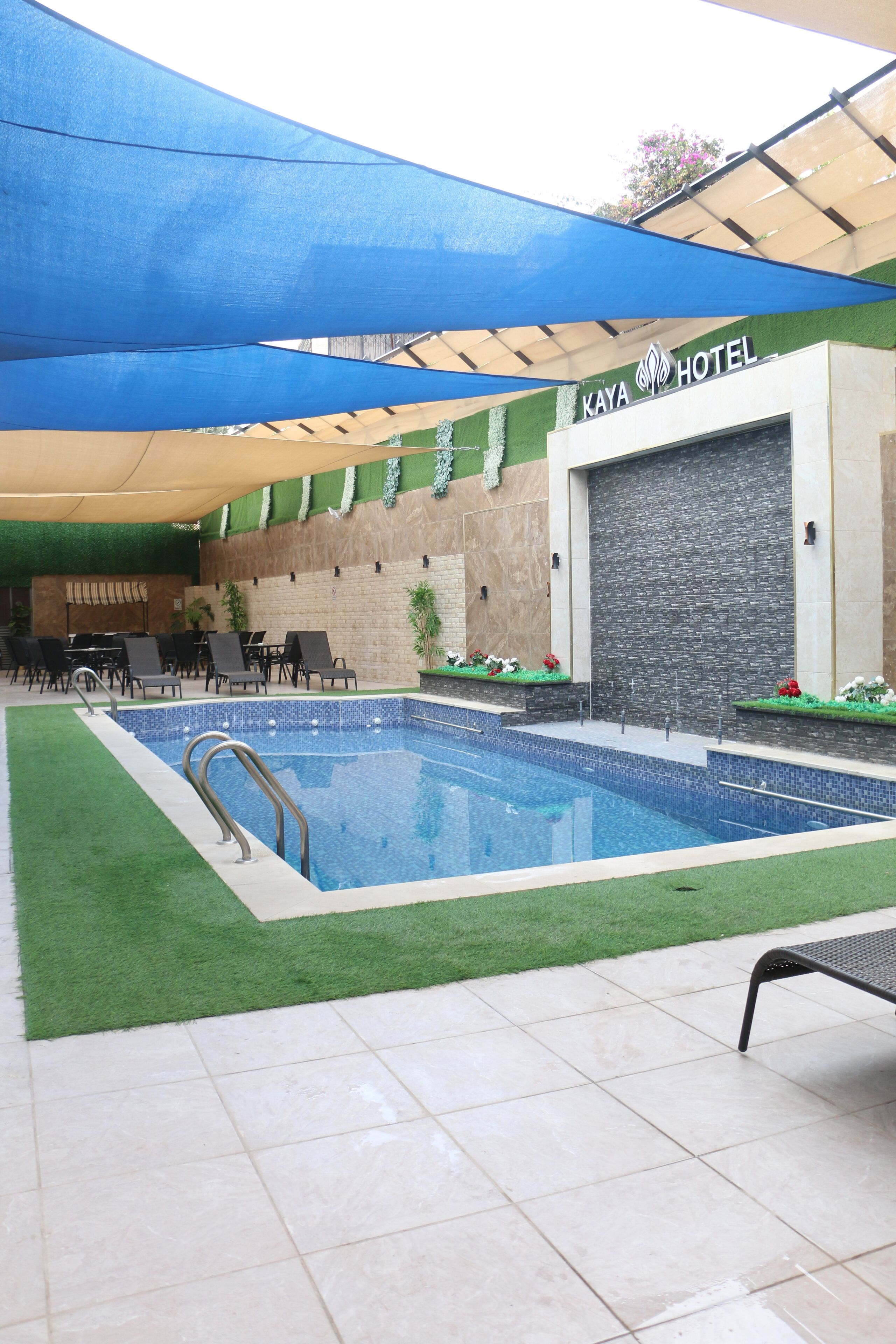 An indoor swimming pool with a blue water feature, surrounded by lounge chairs and a covered seating area.