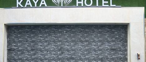 A hotel entrance with a tiled wall and a sign that reads "KAYA HOTEL".