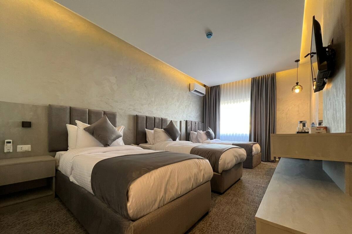 A hotel room with two beds, a small desk, and a large mirror.