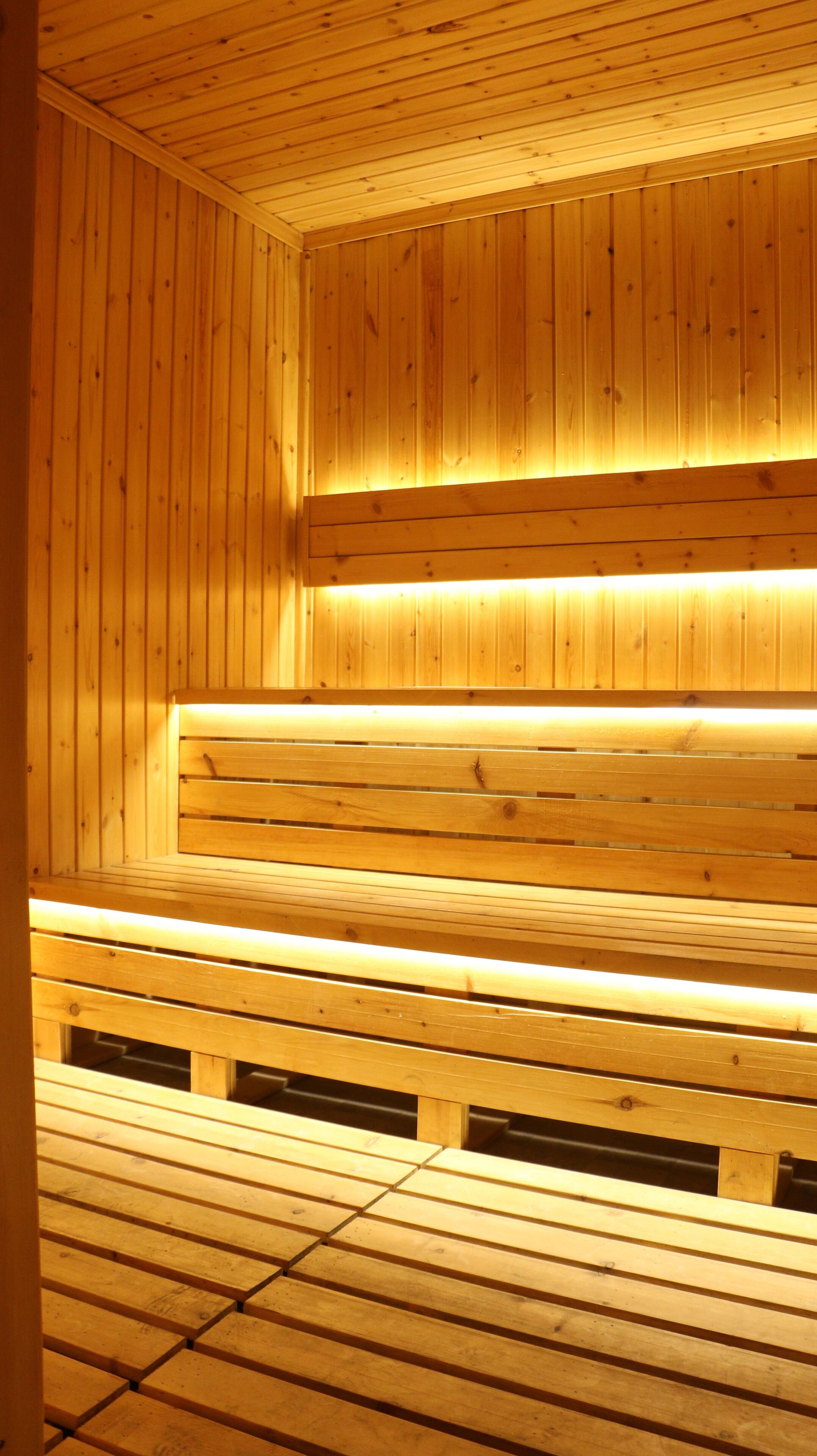 A wooden sauna with benches and a sloped floor.