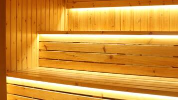 A wooden sauna with benches and a sloped floor.